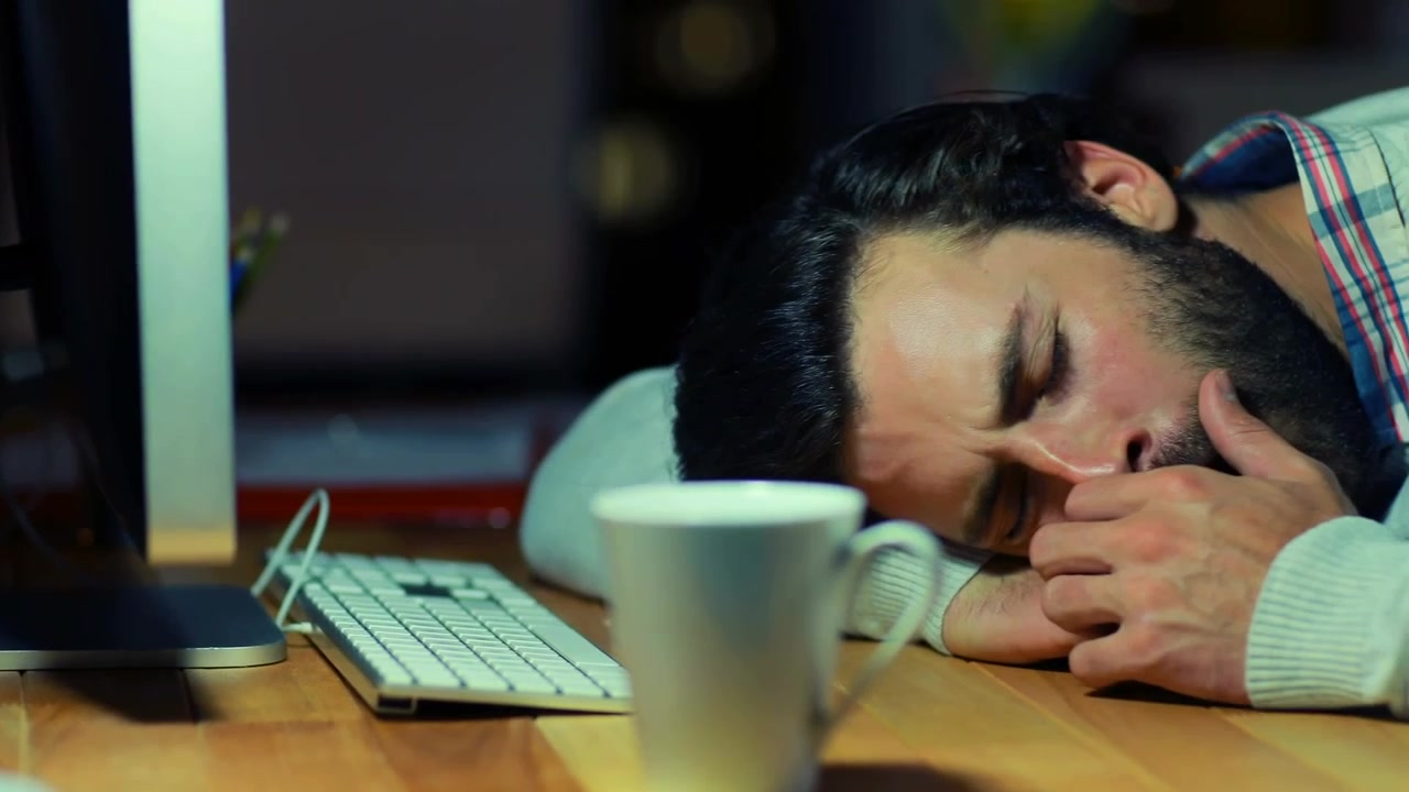 Uomo esausto che dorme alla scrivania in ufficio di notte