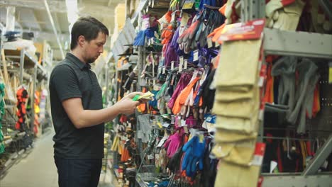 hombre comprando guantes de jardinería en una ferretería