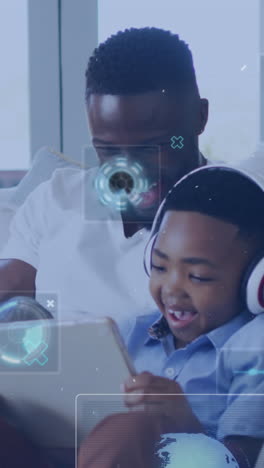 animation of technology icons over happy african american father and son using tablet