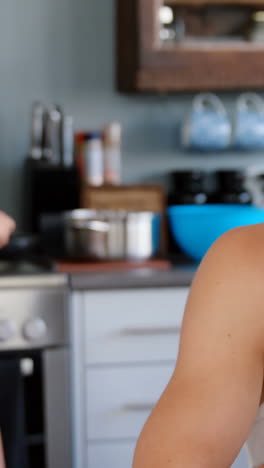 mujer atractiva cocinando mientras el hombre usa el teléfono inteligente