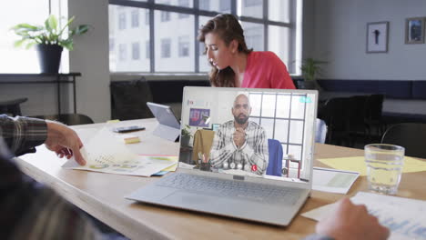 hombre de negocios caucásico en una llamada de video portátil con un colega afroamericano en la pantalla