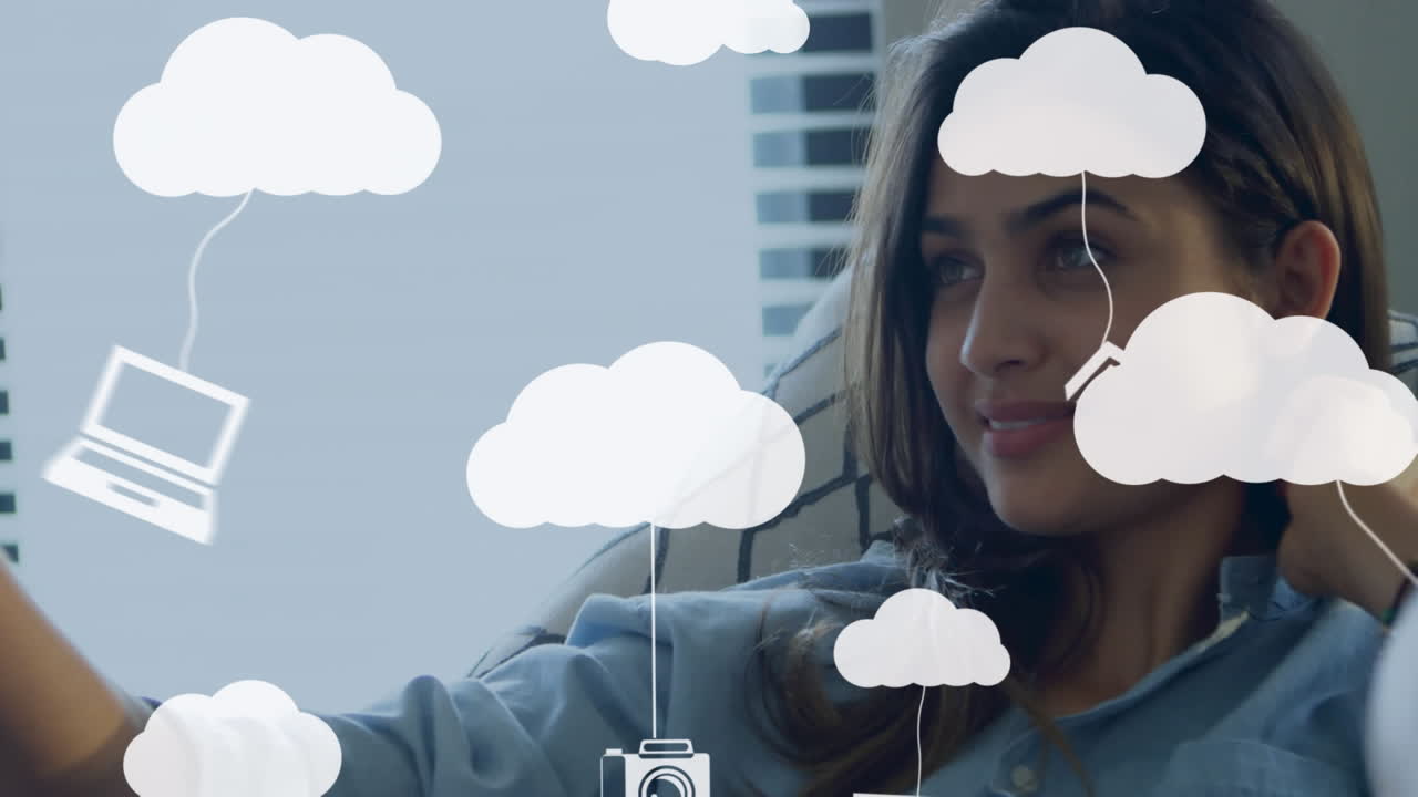 Animation of clouds and media icons over woman using smartphone