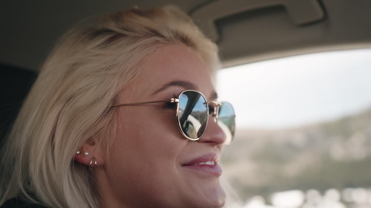 chica con gafas de sol sonriendo mientras conduce un coche