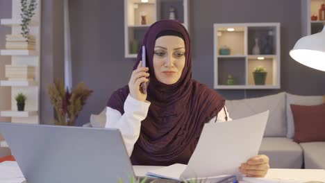 Business-woman-in-hijab-talks-about-work-on-the-phone-in-her-home-office.