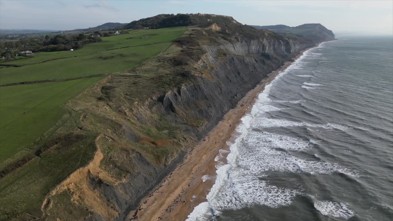 Aerial jib up showing the long Charmouth Beach and the incredible cliff sides near Dorset, UK