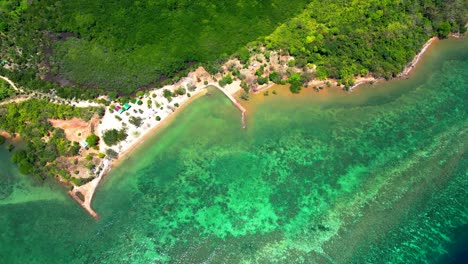 aerial view of a tropical island coastline with clear turquoise water and lush forest