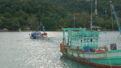 wooden fishing boat towing a sinking boat behind