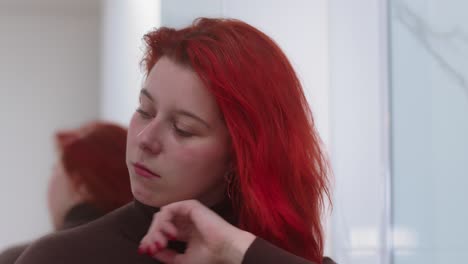 Beautiful-woman-brushing-red-color-hair-in-modern-bathroom,-close-up-view