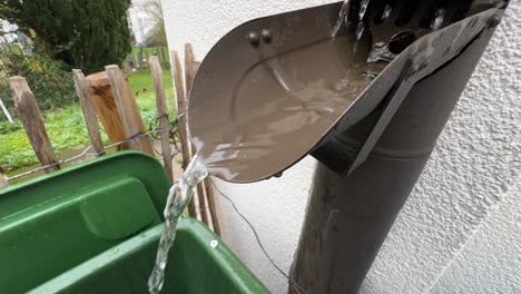 Close-up-shot-of-water-flowing-out-of-a-typical-german-drain-pipe-during-rain