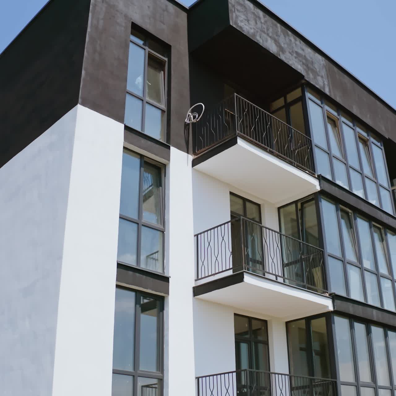 Block of flats on sky background. Modern high-rise apartment building with windows and large balconies. Camera rising up