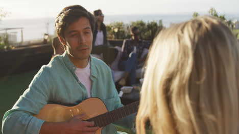 young man playing guitar on a rooftop with his friends