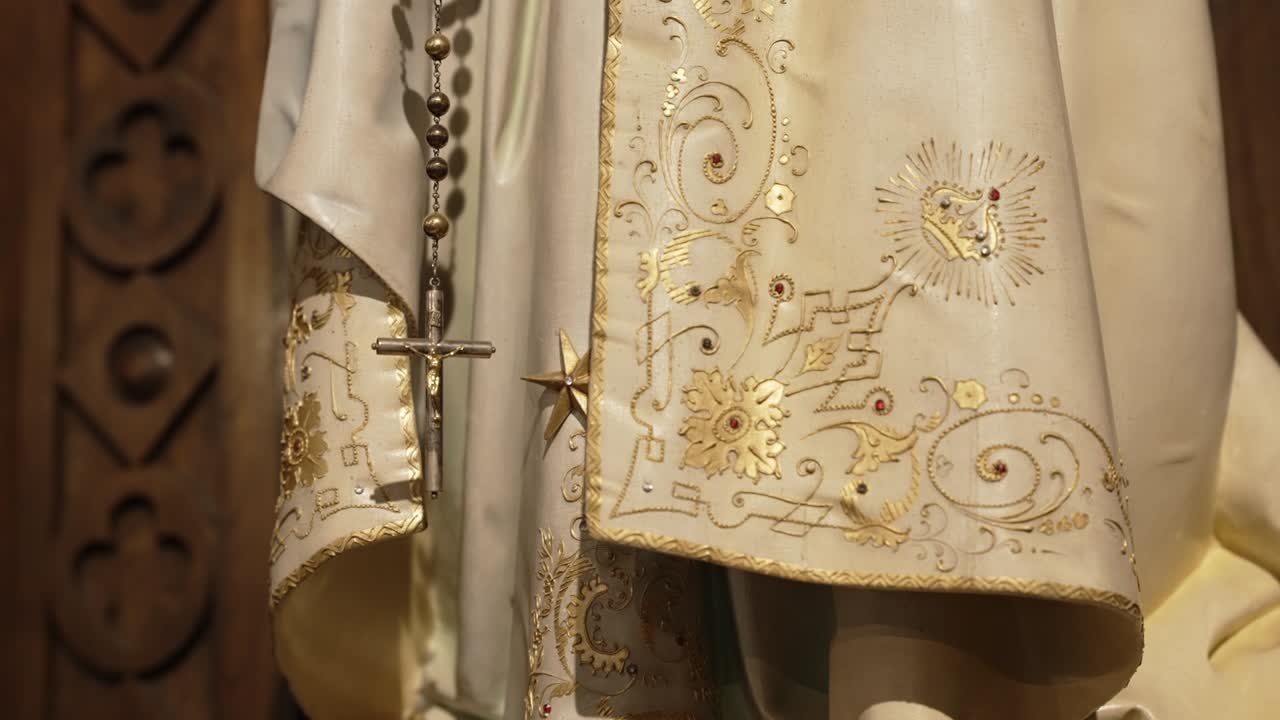 beneath mary’s grace, a rosary rests among golden threads of devotion