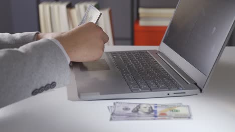 Man-working-at-laptop-counting-dollars.