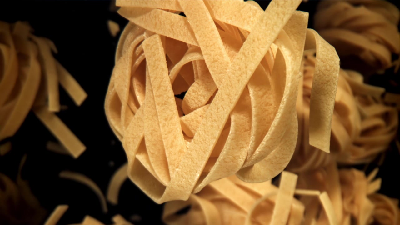 Nidi di tagliatelle secche che cadono al rallentatore