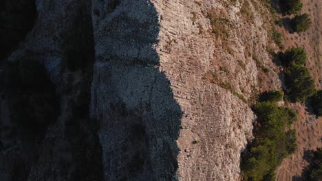 Dramatic-flight-directly-above-and-along-Ana-Ferreira-rocky-stone-steep-jagged-and-pointy-peak-ridge-and-terrain-on-Porto-Santo-island,-archipelago-of-Madeira,-Portugal,-overhead-aerial-approach