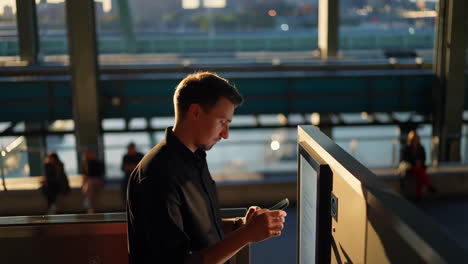 a man uses his smartphone in a public transport station with a city background