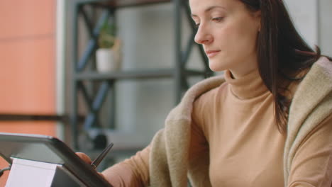 Young-Woman-Sitting-at-Her-Desk-She's-Drawing-Writing-and-Using-Pen-with-Digital-Tablet-Computer.-Hands-with-Pen