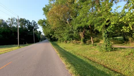 riding a bike on a country road with a car zooming by on the left