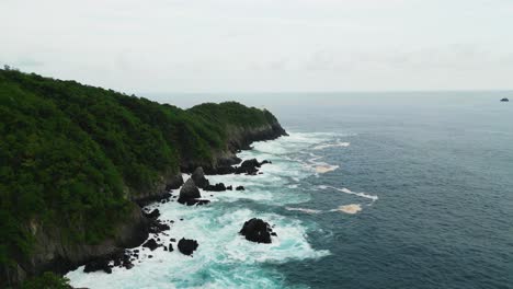 shore of the pacific ocean in zihuatanejo, mexico. where waves crash against the rocks and the jungle grows over them. 4k drone shot of the pacific ocean