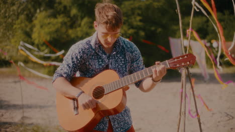 un joven guapo tocando la guitarra en la playa.