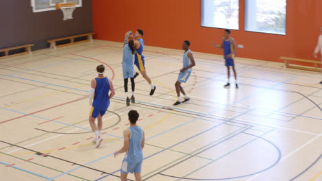 multiracial male basketball players in gym and fouling one player, with male coach observing game