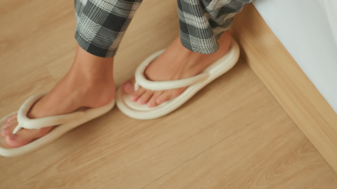 En person forbereder sig forsigtigt på at forlade stedet lydløst. Personen tager forsigtigt sko på, før den lydløst forlader rummet. Gæsten tager roligt og lydløst fodtøj på, før den stille går væk fra sengen.