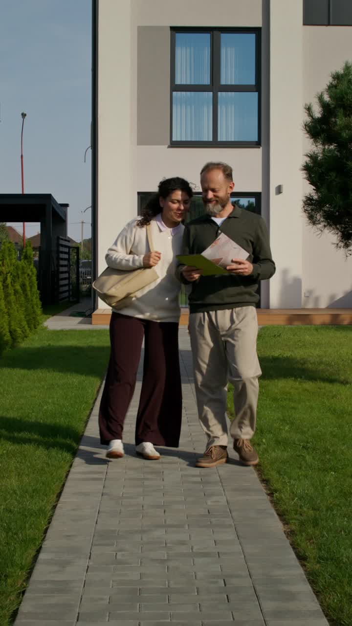 Couple Discussing Property in Front of Modern Home