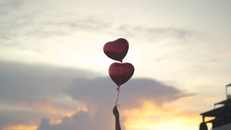 two heart-shaped balloons float in the air held by a woman