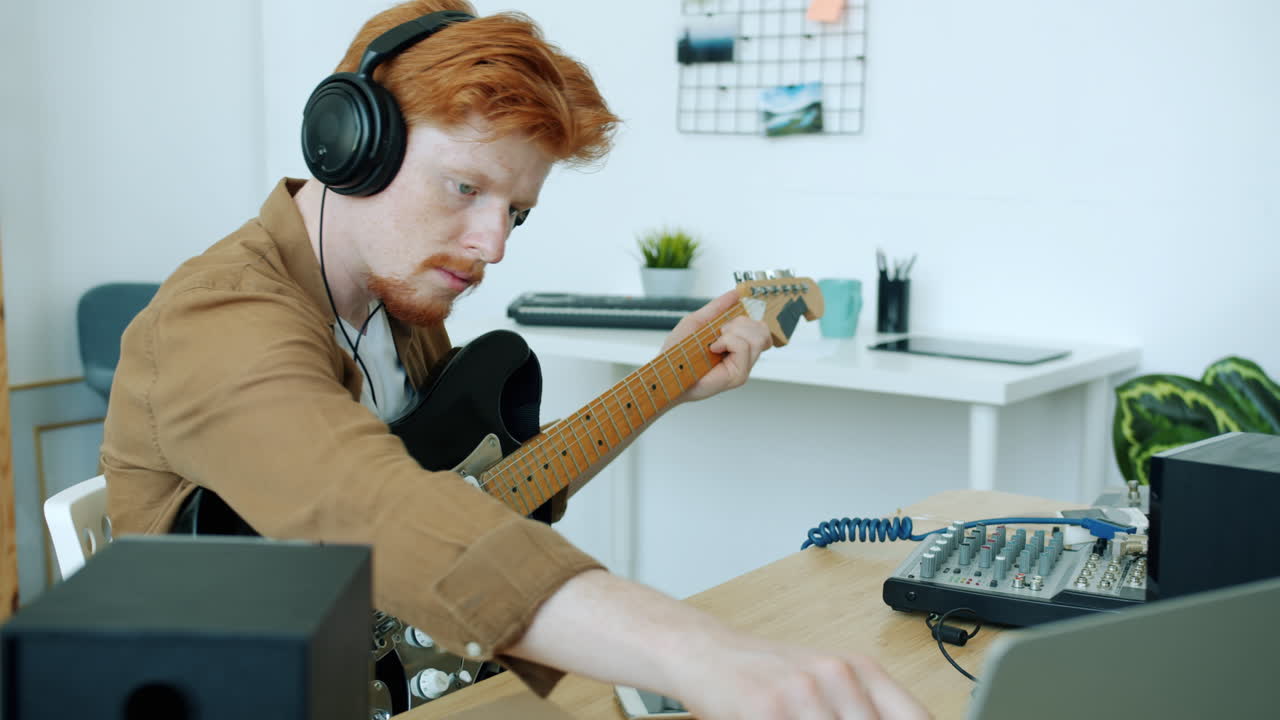 Man playing guitar in a home recording studio