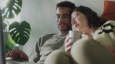 couple cuddling and using laptop on couch