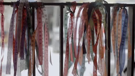 Close-up-of-tapes-of-Lord-of-Bonfim-tied-to-railing,-swaying-in-wind