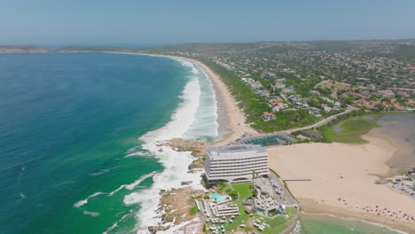 Forwards-fly-above-sea-coast.-Waves-washing-sand-beaches.-Aerial-footage-of-vacation-resort-and-residential-borough.-Plettenberg-Bay,-South-Africa