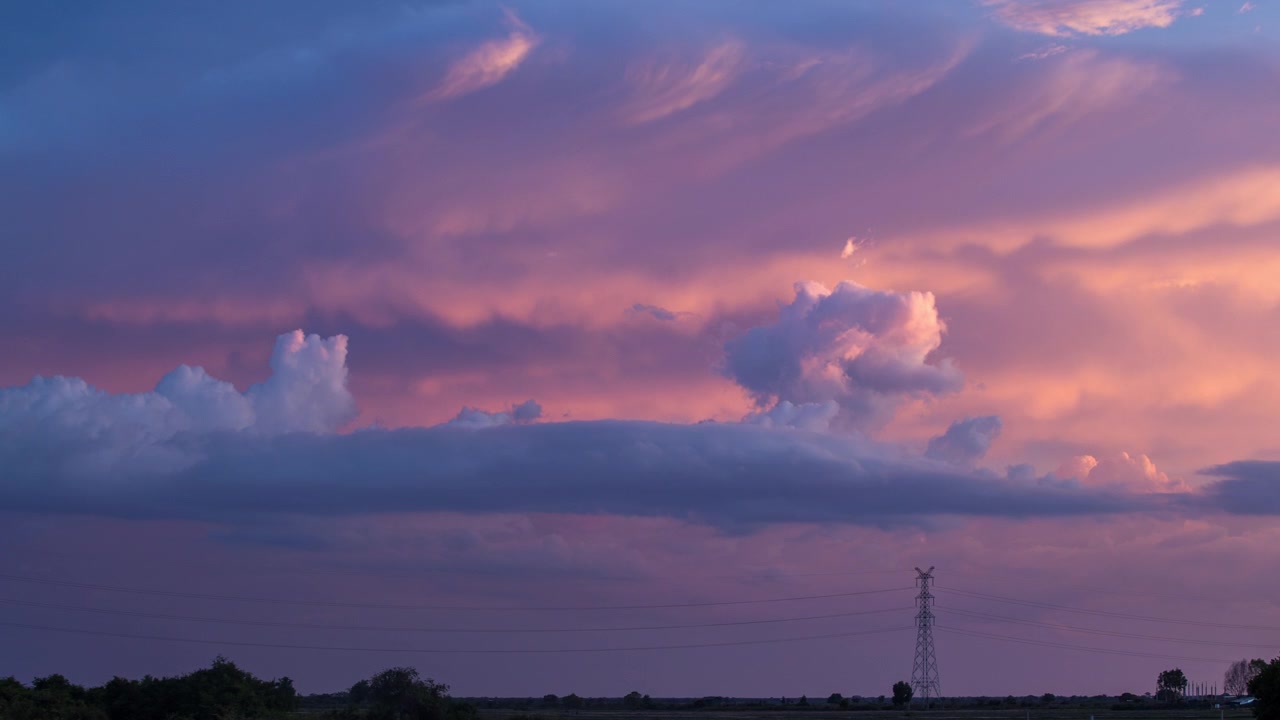 Time-lapse di un paesaggio nuvoloso in movimento durante un tramonto rosso riflesso che svanisce, con la sagoma di un traliccio elettrico, cieli della Cambogia, Asia