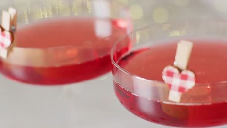 Video-of-two-red-drinks-in-cocktail-glasses-with-heart-clips,-selective-focus-with-copy-space