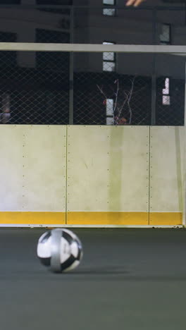 lower angle view of man skillfully kicking soccer ball into goalpost as ball bounces up, scene features metallic fence, residential building