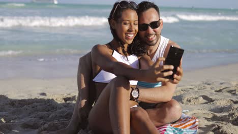 Happy-diverse-couple-taking-selfie-on-beach