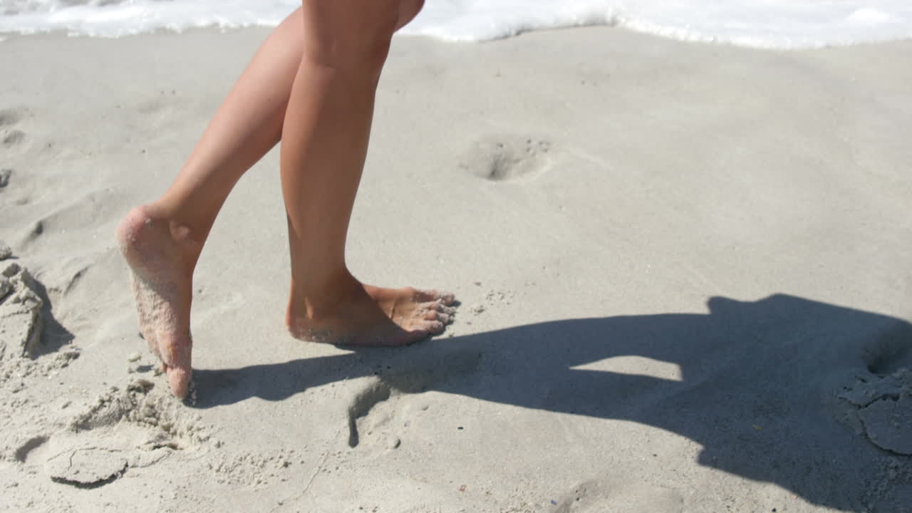 Donna che cammina sulla spiaggia a piedi nudi