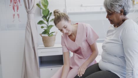 fisioterapeuta feliz y diversa tratando la pierna de una paciente anciana, cámara lenta