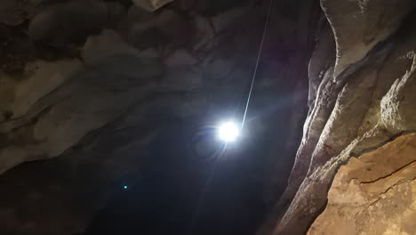 a lone caver using single rope technique (srt) descends into the pitch-black depths of anxiety state cave in chiang mai, thailand. adventure, mystery, and the thrill of exploration.