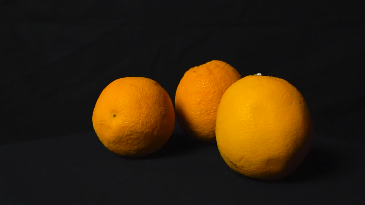 tres naranjas en fondo oscuro