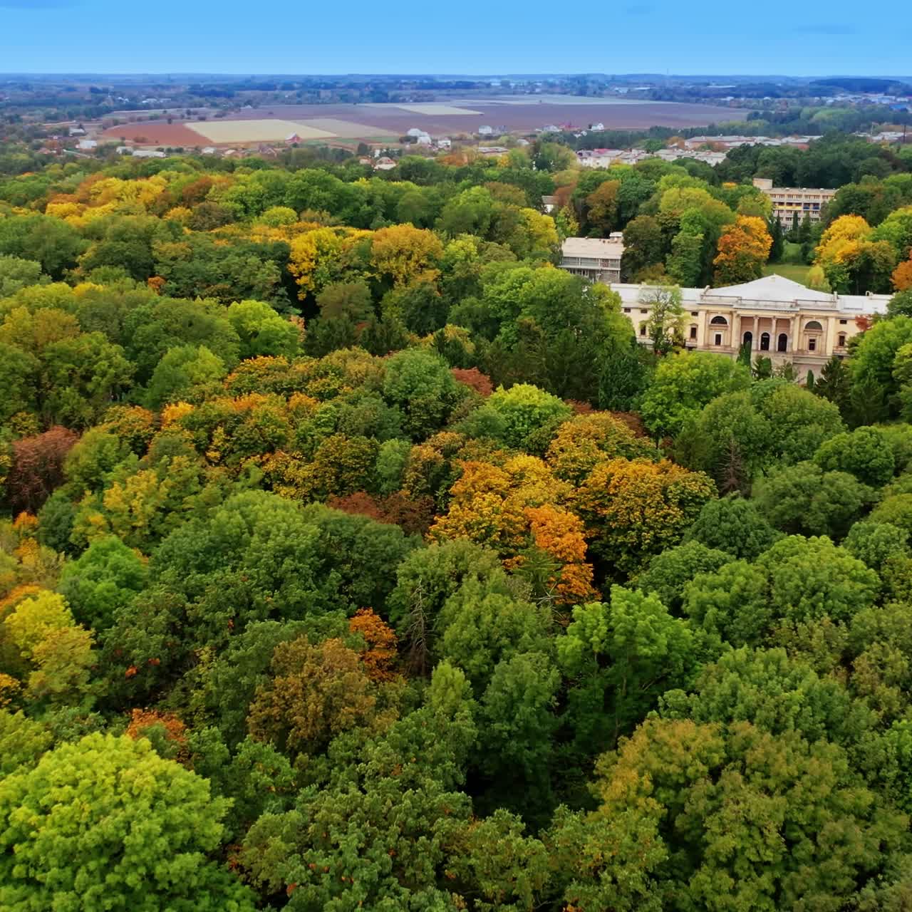Historical palace in the beautiful green park. Cityscape and agricultural fields at backdrop. Aerial view