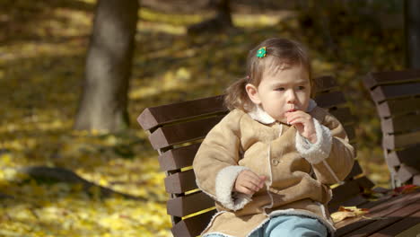 niña lamiendo piruleta en el parque de otoño