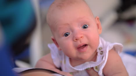 baby raising head and looking with big blue eyes