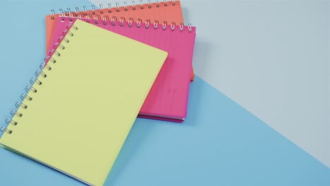 überblick über farbenfrohe notizbücher auf blauem hintergrund in zeitlupe