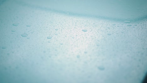 macro slider shot of rain droplets on blue metal car hood shot in 25 fps