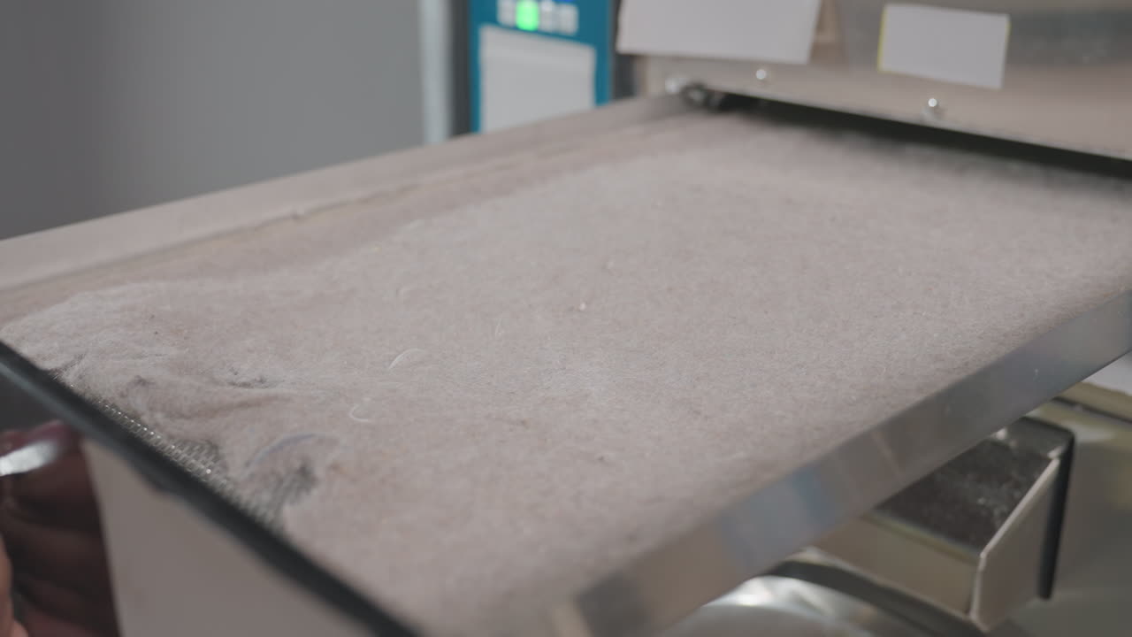 High angle view staff hands unlocking washer filter drawer with key, removing filter, wiping interior, ensuring maintenance and hygiene inside laundromat with machines during routine service