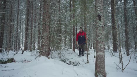 mochilero noruego con su perro en un bosque cubierto de nieve
