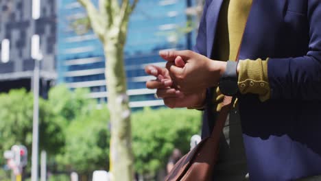 Midscetion-of-african-american-woman-disinfecting-hands-in-the-street