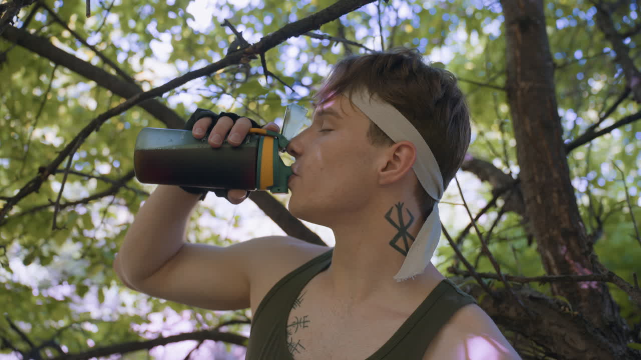 Adventurer wearing headband pauses under leafy canopy, closes eyes and draws deep sip of coffee from water bottle, throat moving with passion, sunlight filtering through branches creating serene rest
