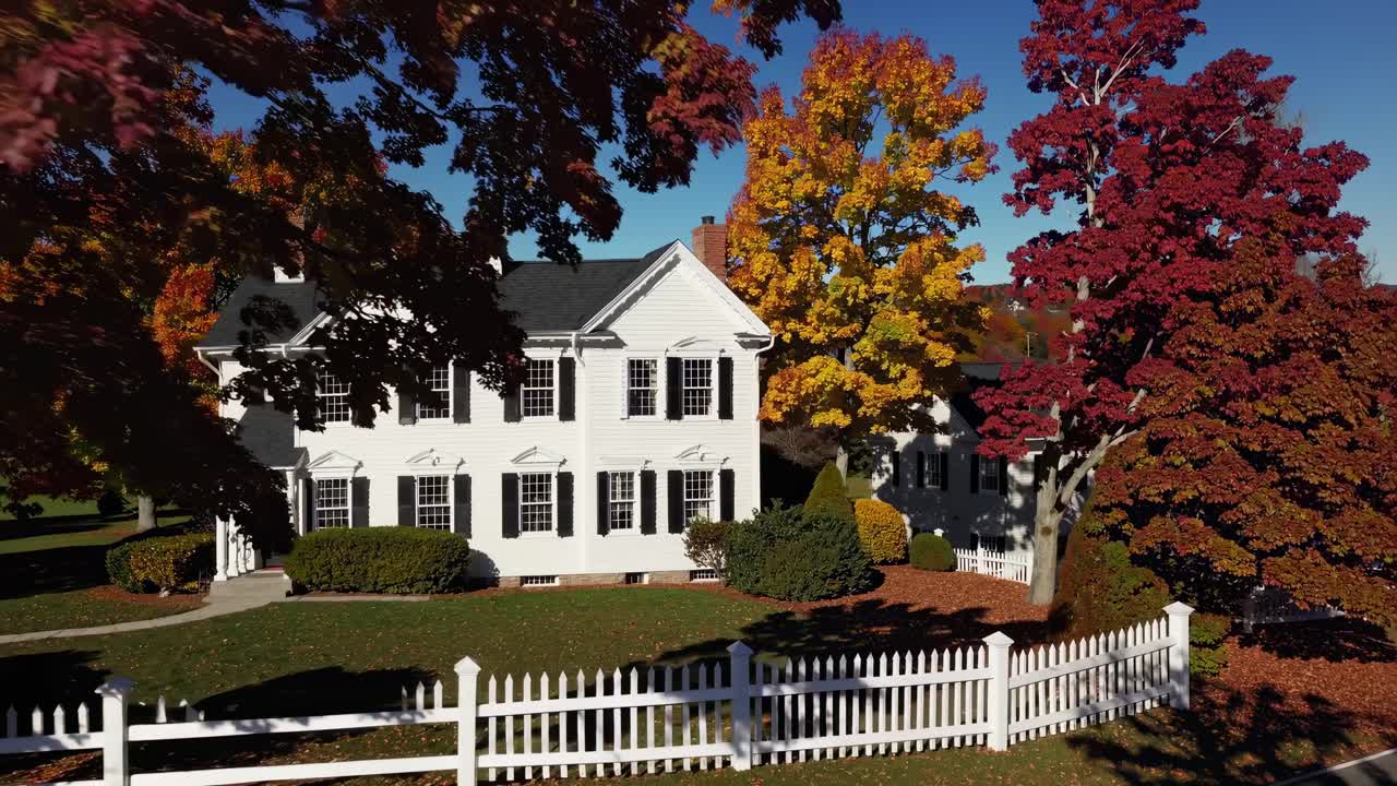 Aerial video captures vibrant autumn foliage over a quaint rural landscape
